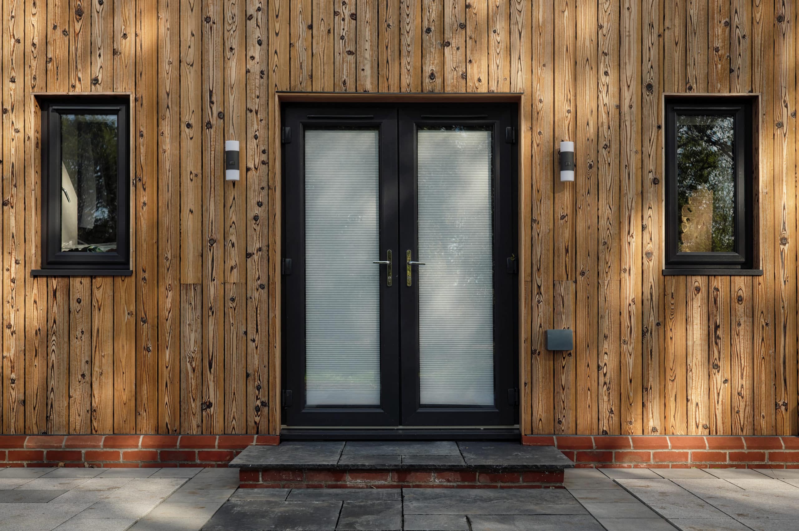 Eingangstür eines Hauses, das mit hellem Holz als Fassadenmaterial ausgestattet ist
