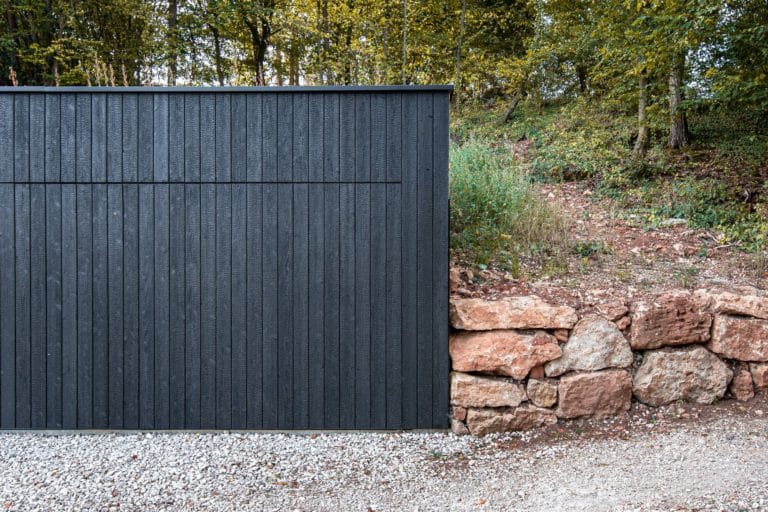 Garage mit schwarzem Holz mit Bäumen im Hintergrund