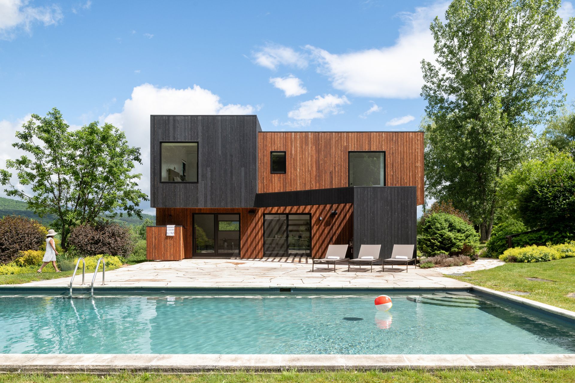 Haus mit schwarzer und hellbrauner Fassade und einem großen Pool auf der Vorderseite