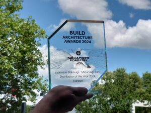 Hand mit Nakamoto Forestry Award 2024 vor blauem Himmel